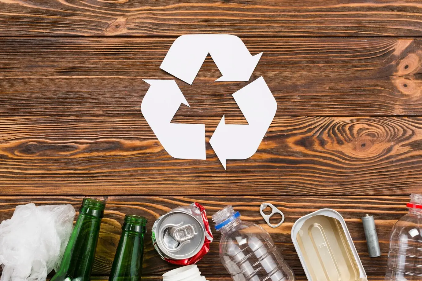 Recycling-Symbol und Müll vor hölzernem Hintergrund